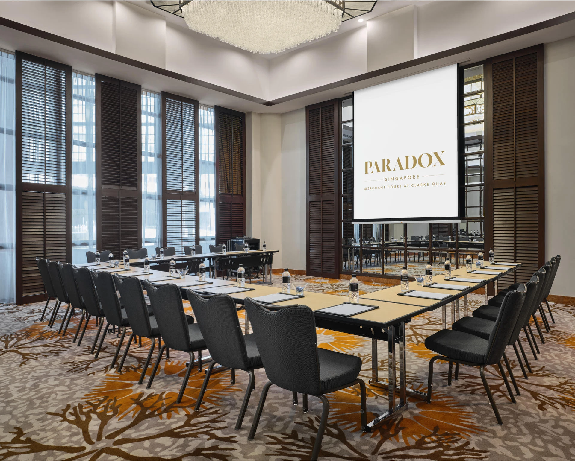 Paradox Singapore Inkwood Room in U-shape meeting setup with wooden shutters and crystal chandelier