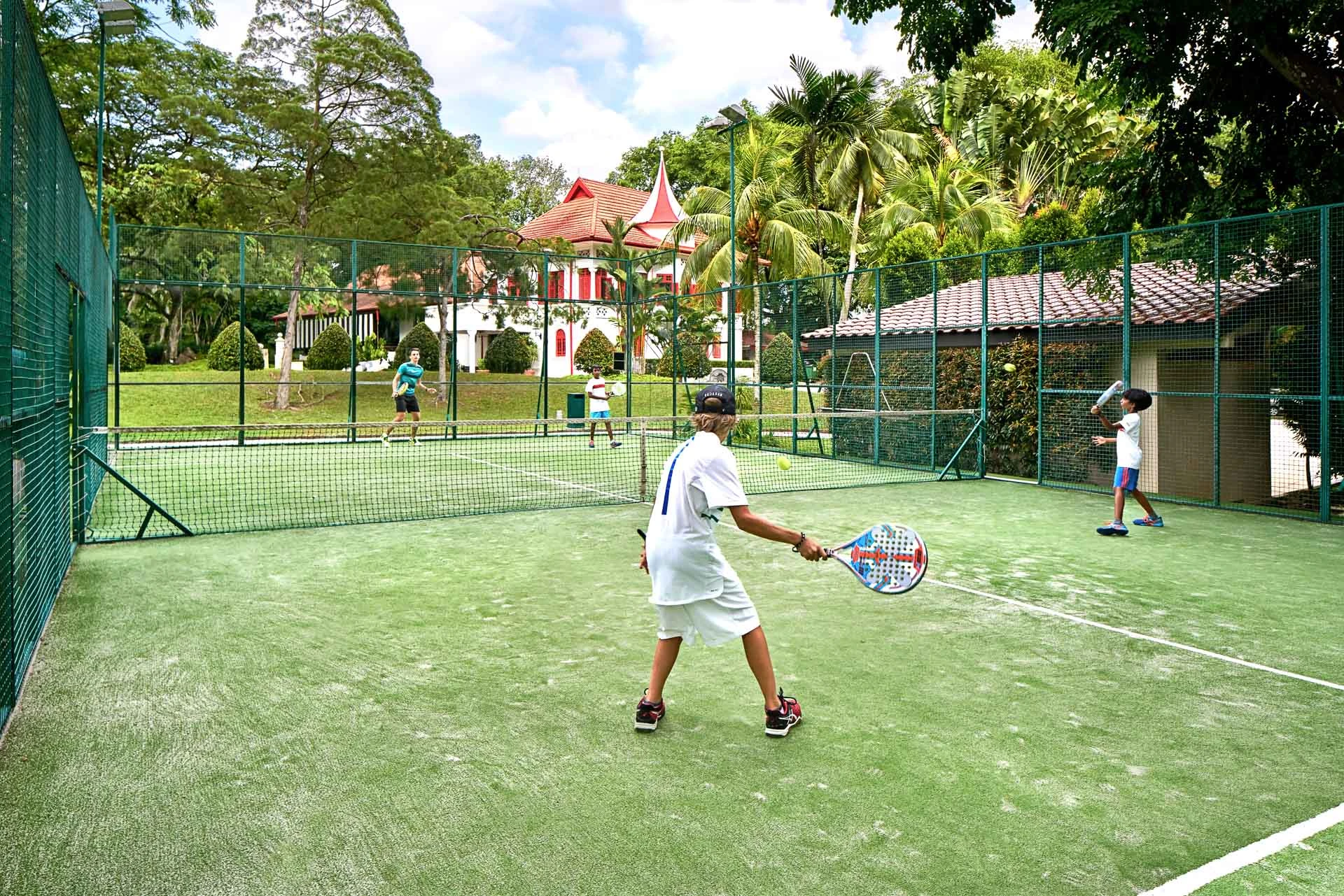 Padel doubles match with heritage clubhouse turret beyond