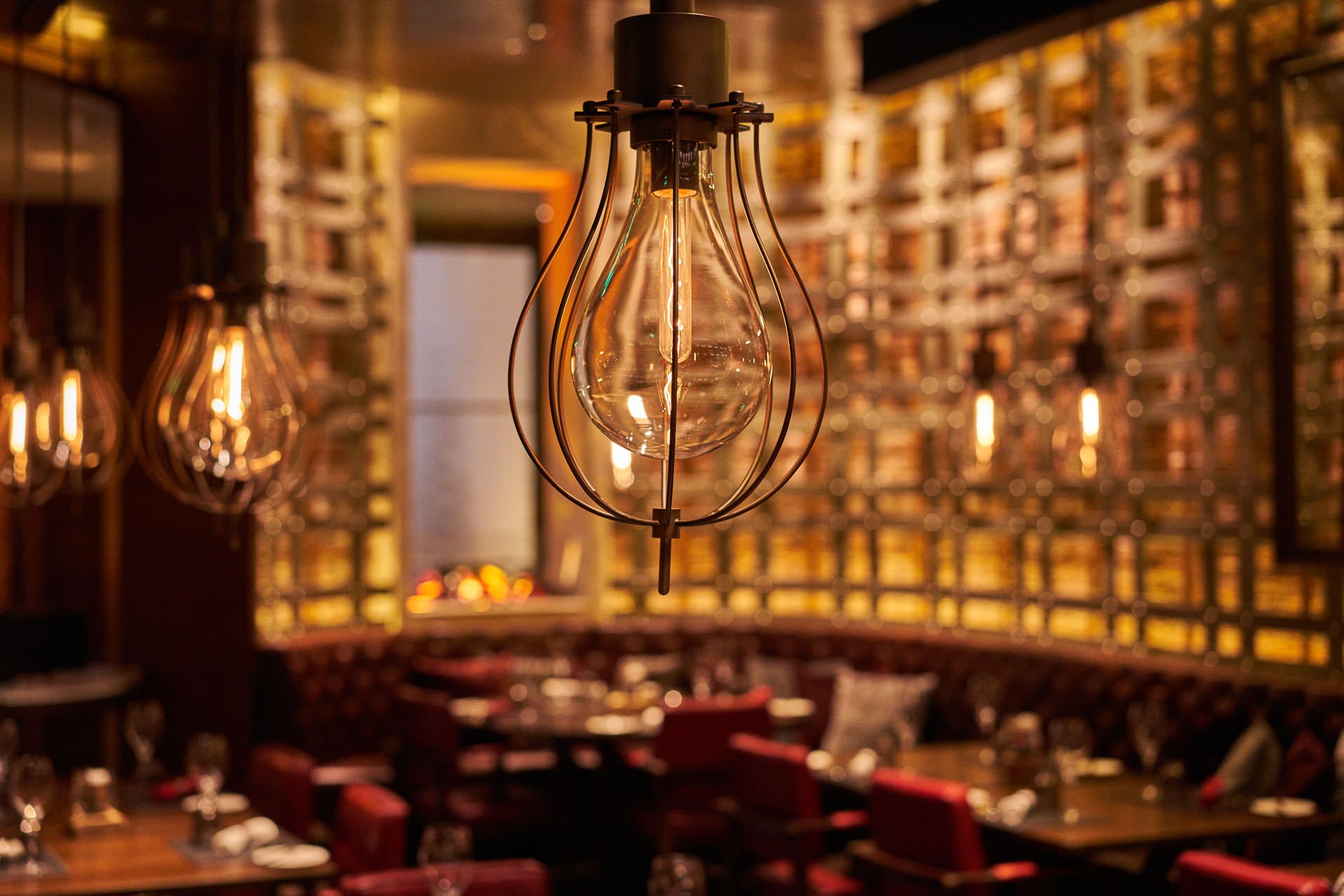 Edison cage pendant with burgundy banquette and golden lattice bokeh