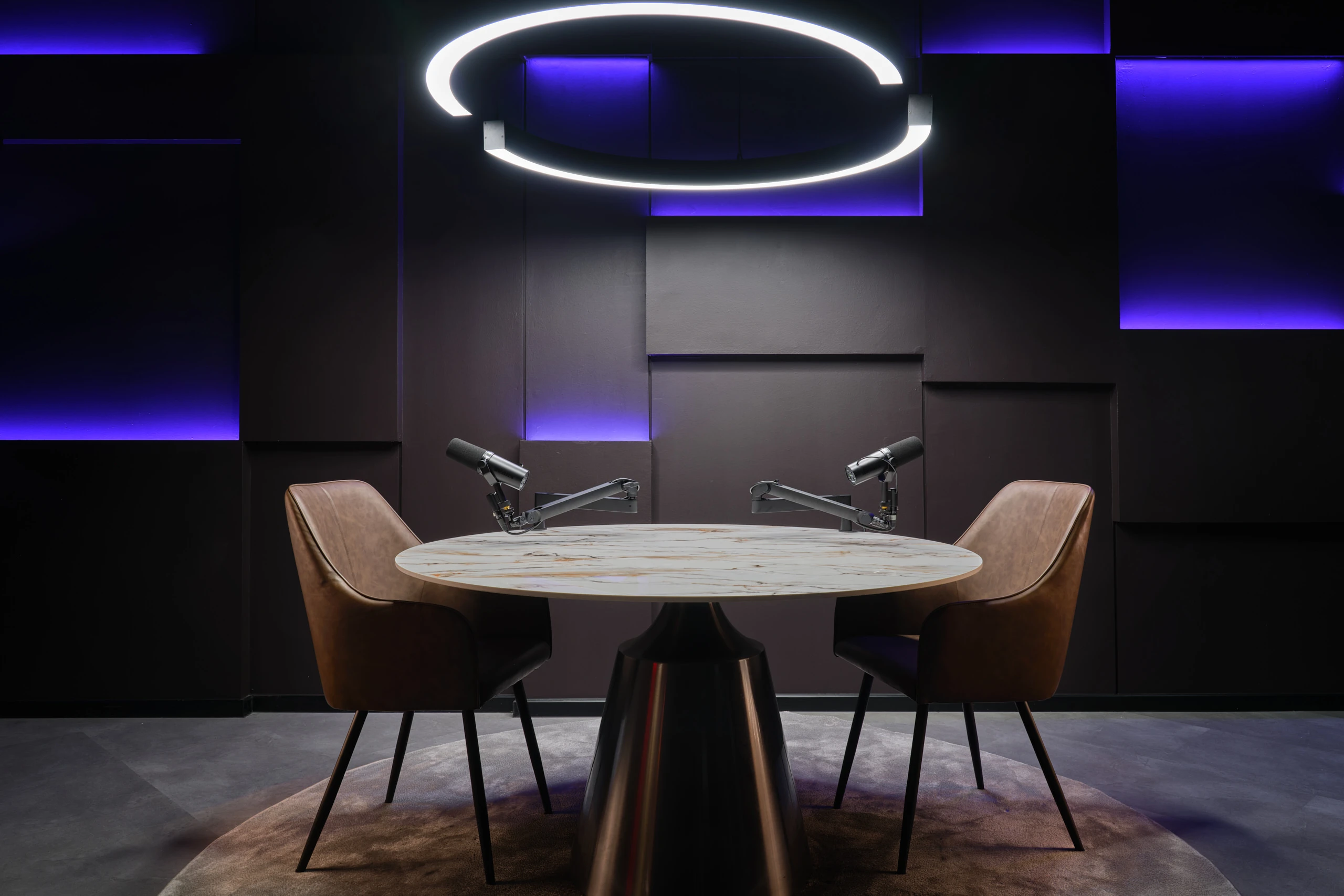 Futuristic dark podcast studio with geometric wall panels and blue LED accents