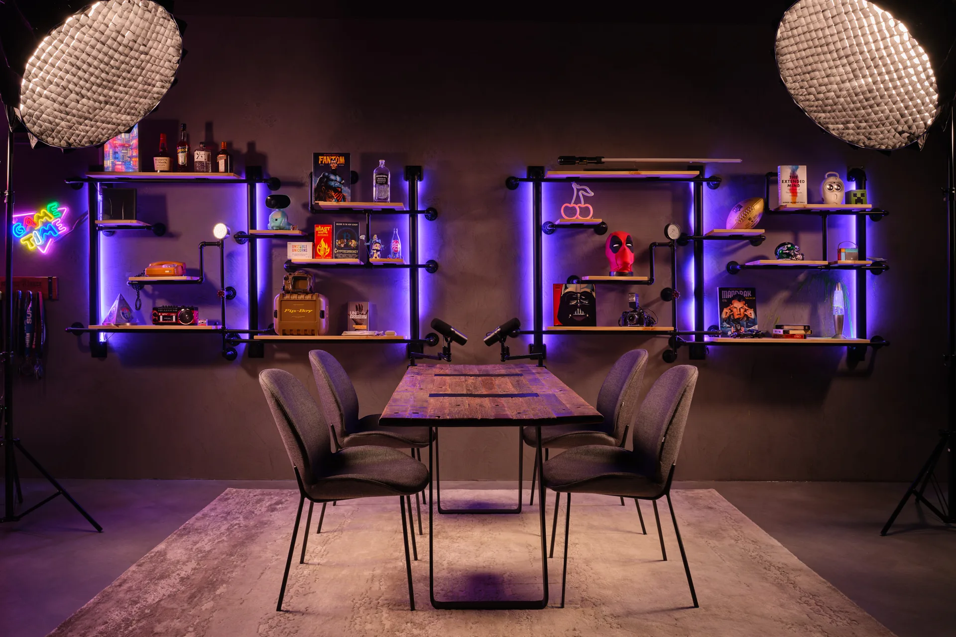 Industrial gaming podcast studio with purple LED pipe shelving and pop culture memorabilia