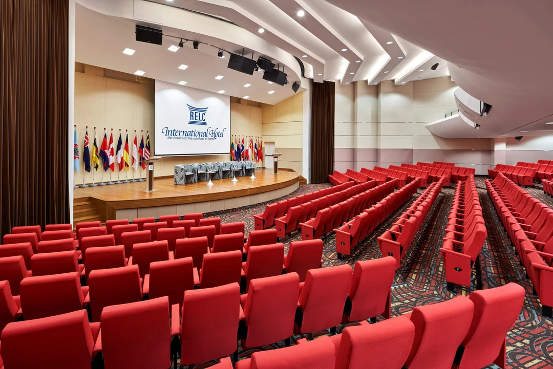Auditorium with red seats, curved stage and international flags