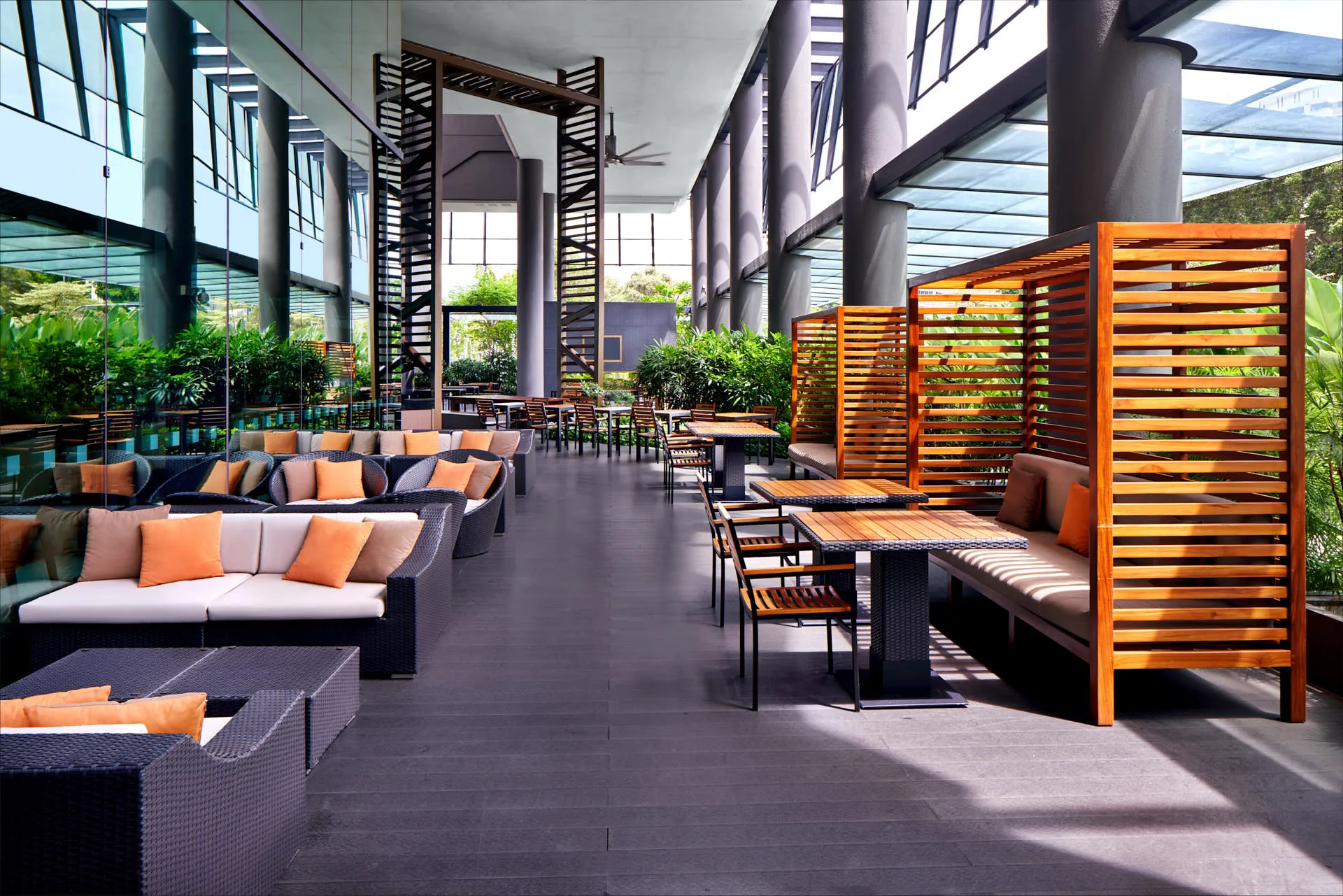 Covered terrace lounge with wicker sofas, slatted screens and tropical greenery — Holiday Inn Express Clark Quay hospitality photography