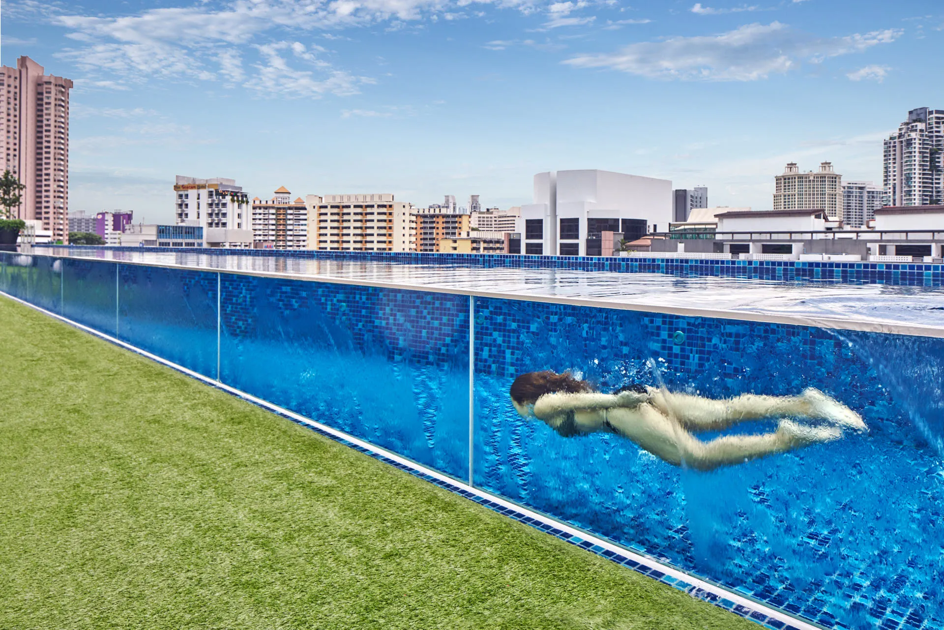 Swimmer in glass-walled rooftop pool with city views — Holiday Inn Express Clark Quay lifestyle photography