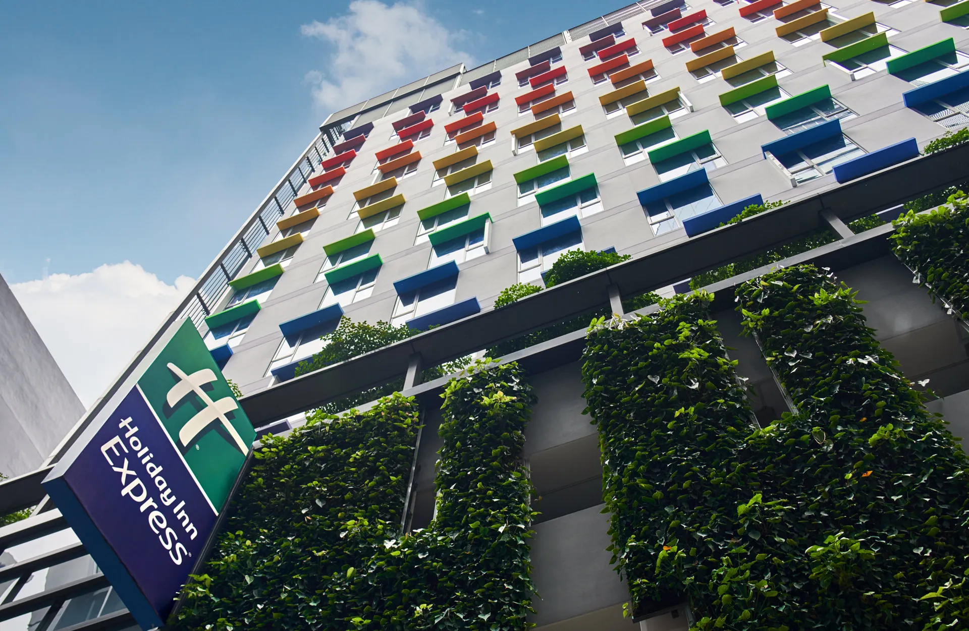 Vibrant multicoloured facade with vertical garden and brand banner — Holiday Inn Express Orchard architectural photography