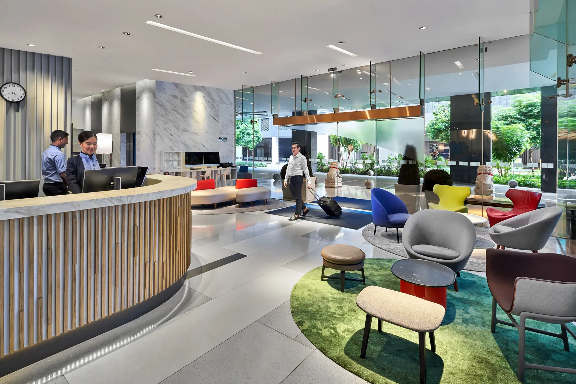 Bright lobby with colourful lounge chairs, curved desk and glass walls — Holiday Inn Express Orchard hotel photography