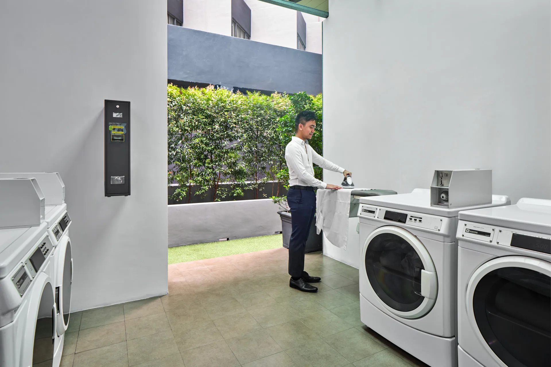 Guest ironing in self-service laundry with garden view — Holiday Inn Express Orchard lifestyle photography