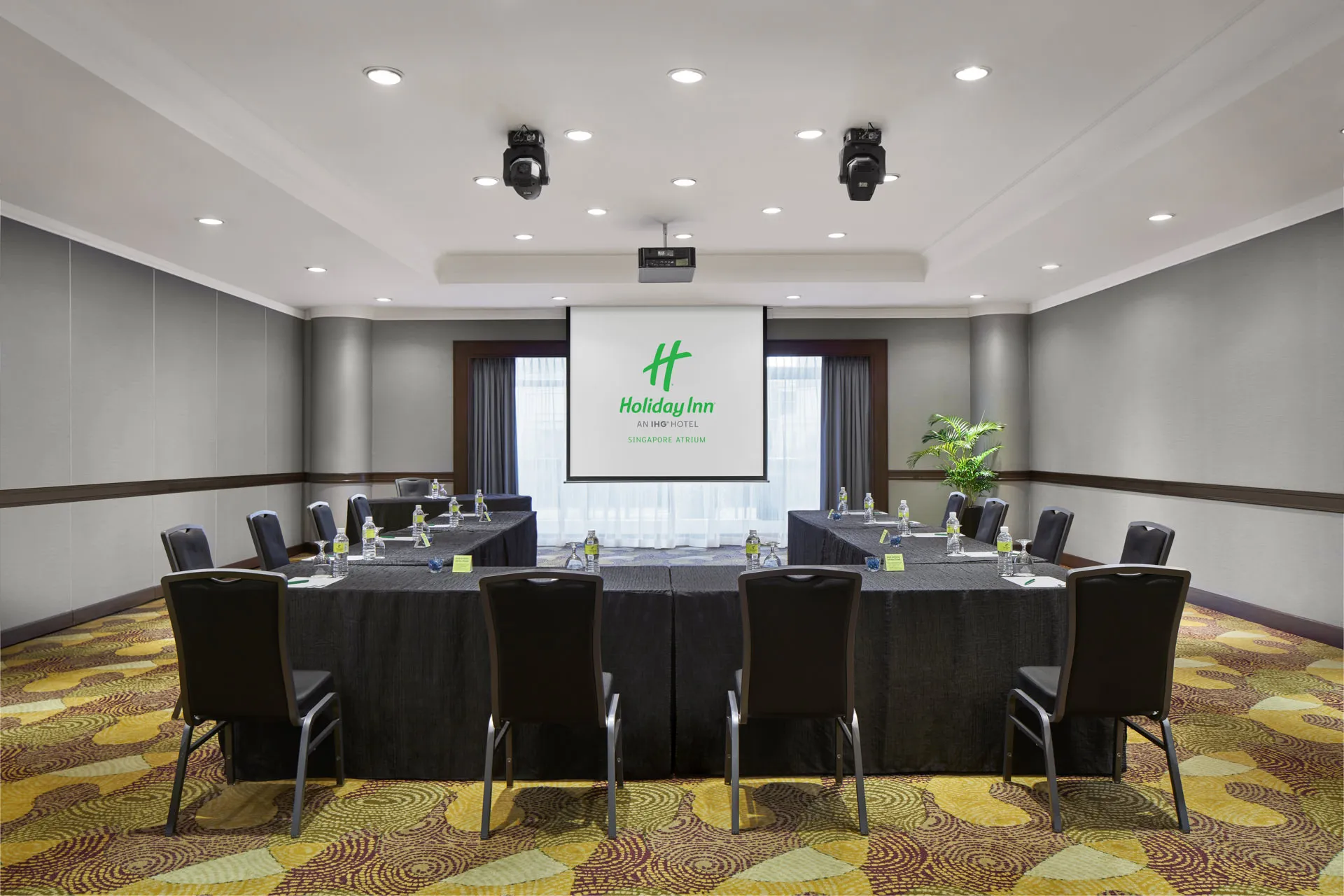 Meeting room in U-shape setup with projector screen and spotlights — Holiday Inn Atrium Singapore function room photography