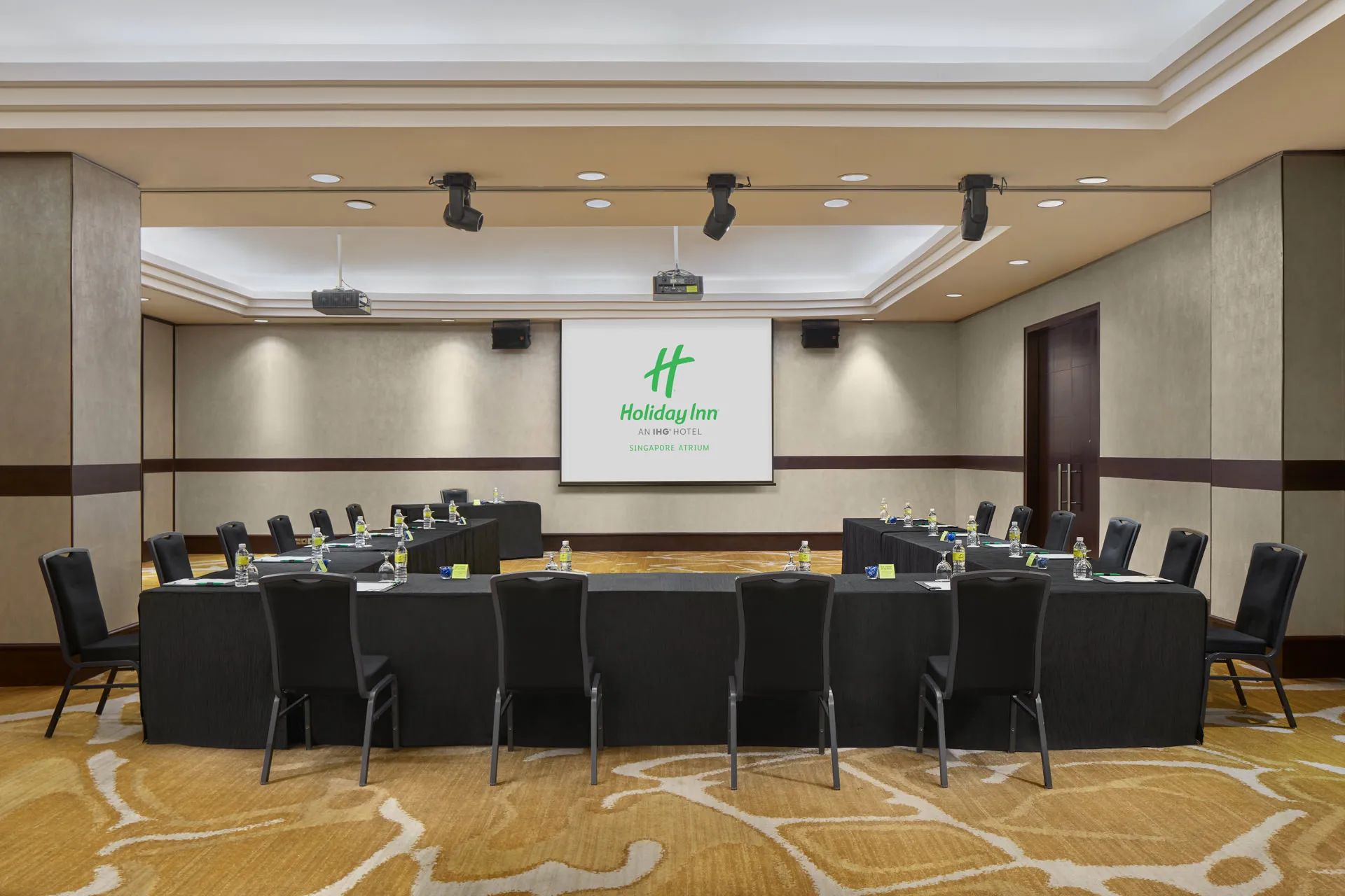 Ballroom meeting setup in U-shape with projection screen and accent lighting — Holiday Inn Atrium function room photography