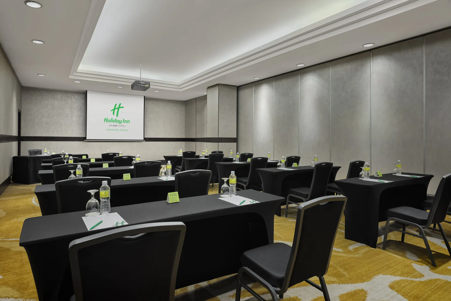 Meeting room in classroom layout with projector and silver wall panels — Holiday Inn Atrium Singapore function room photography
