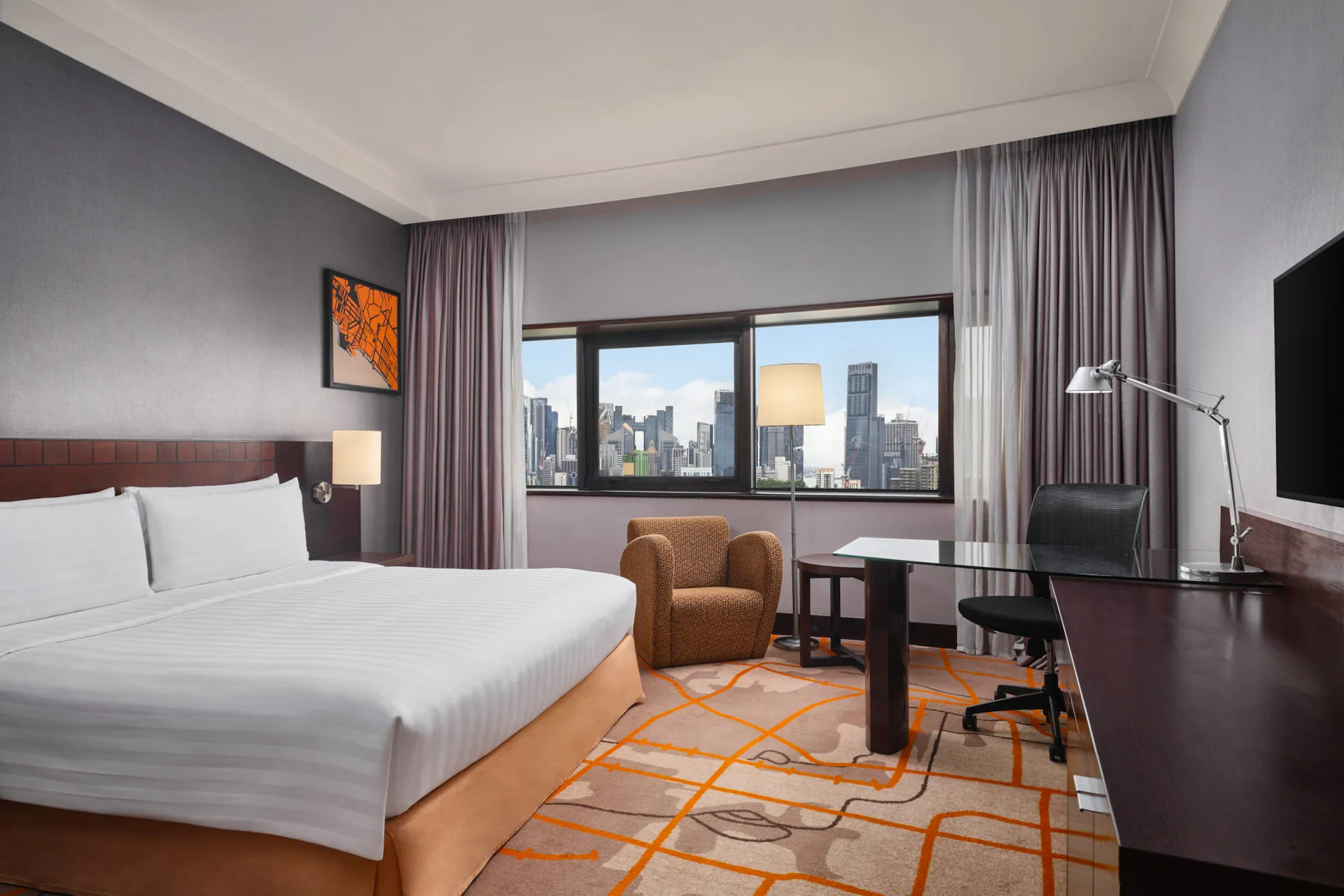 King room with orange accent runner, armchair and panoramic city view — Holiday Inn Atrium Singapore hotel photography
