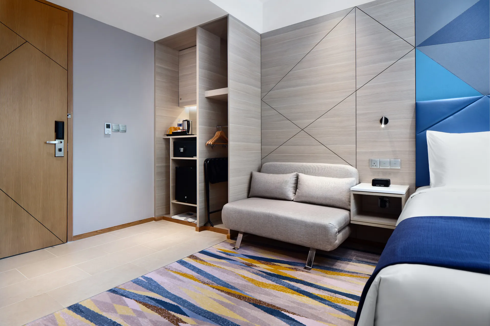 Accessible room entry with open wardrobe, minibar niche and geometric wall panels — Holiday Inn Express Serangoon hotel photography