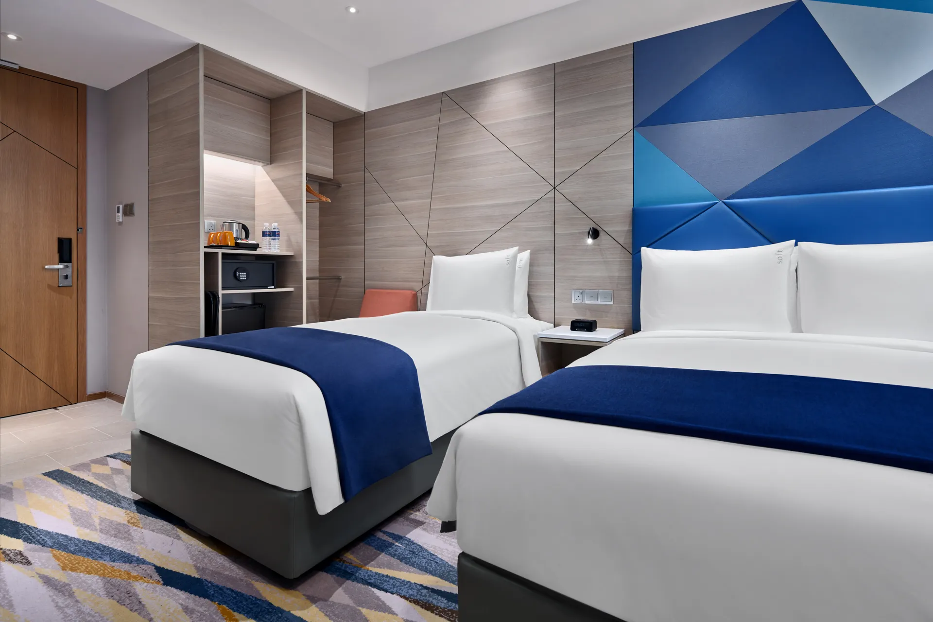 Twin room with blue headboard, orange chair and striped carpet — Holiday Inn Express Serangoon hotel photography