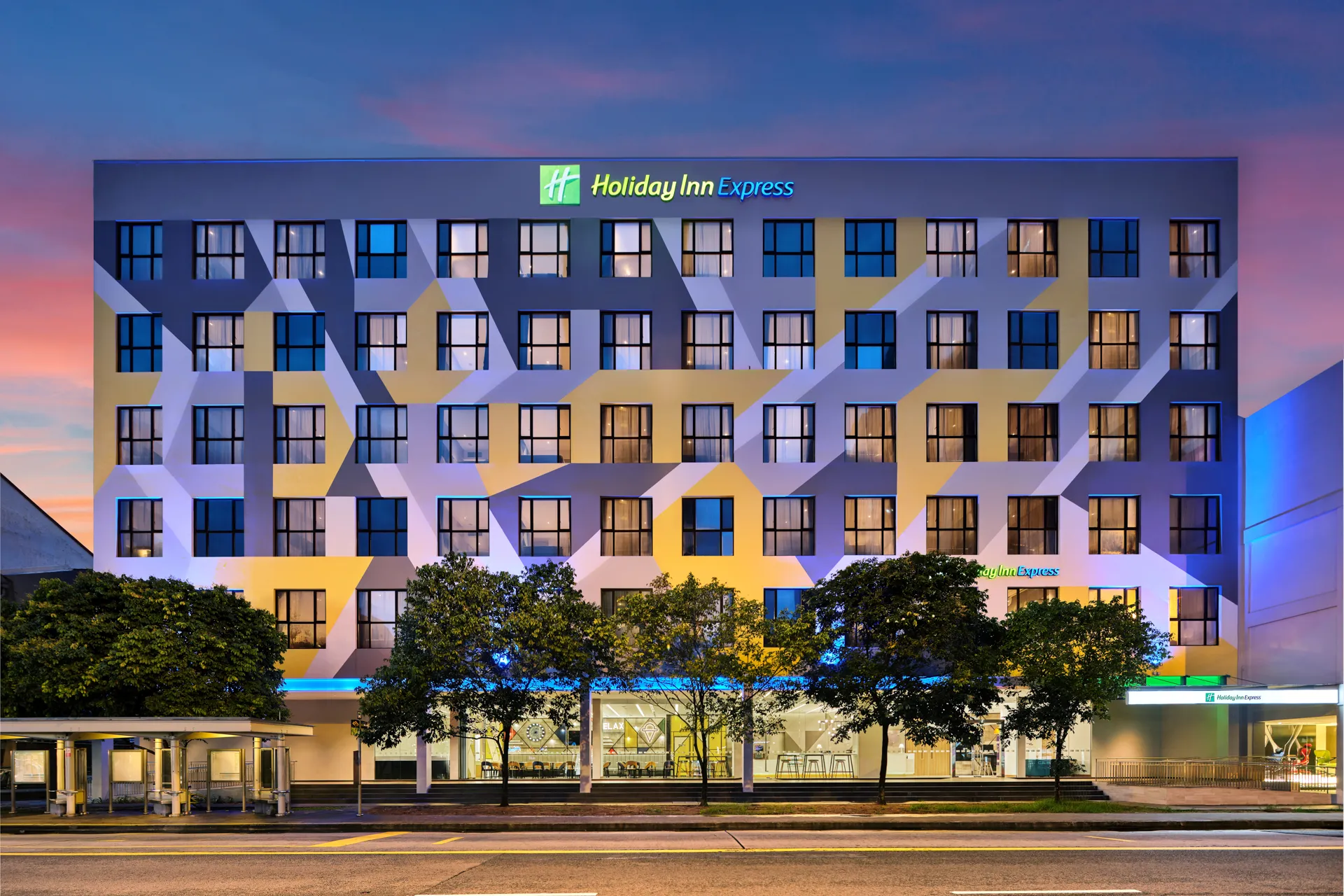 Hotel exterior at twilight with glowing room lights and sunset sky — Holiday Inn Express Serangoon architectural photography