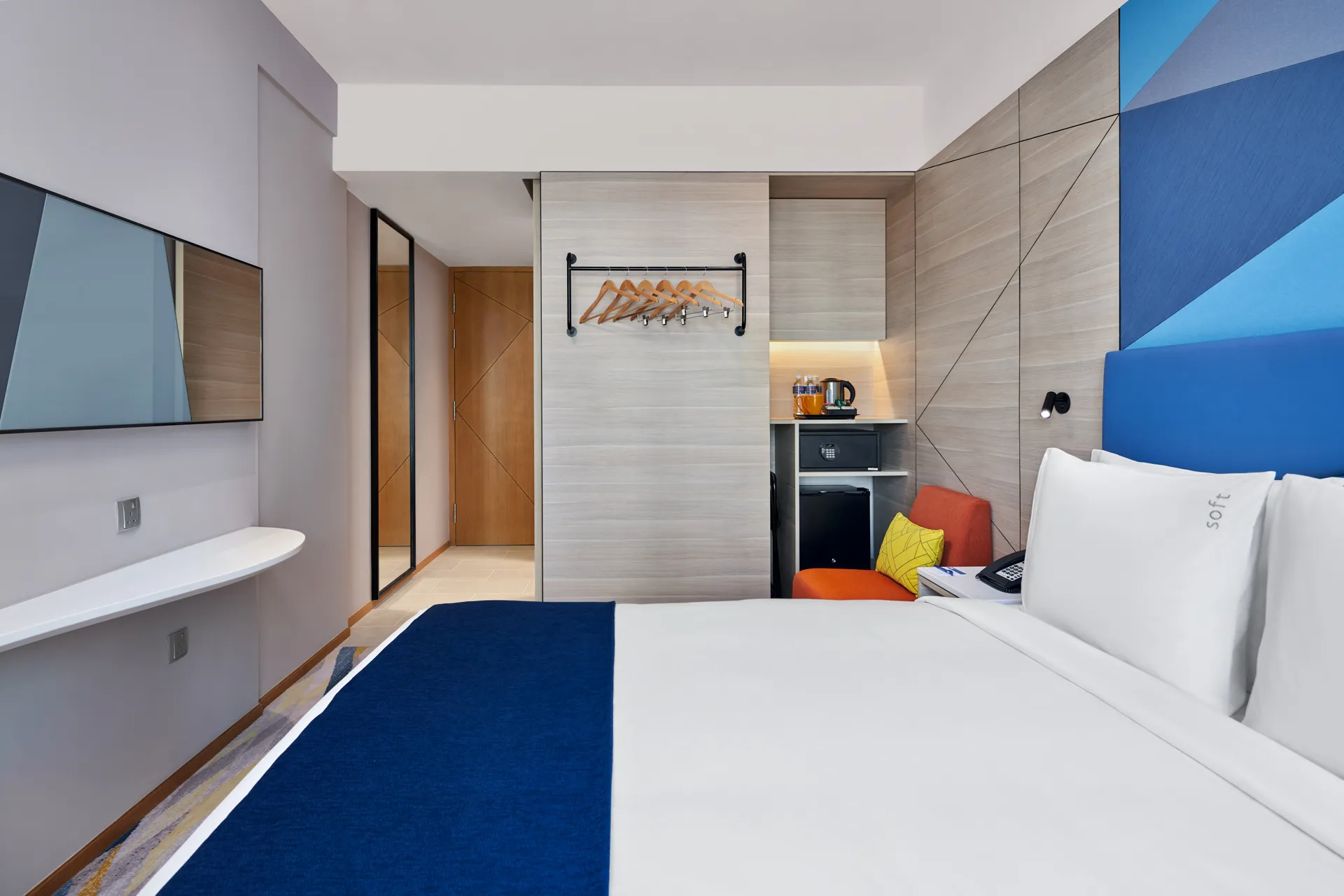 Queen room with blue headboard, floating desk and wood panel walls — Holiday Inn Express Serangoon interior photography