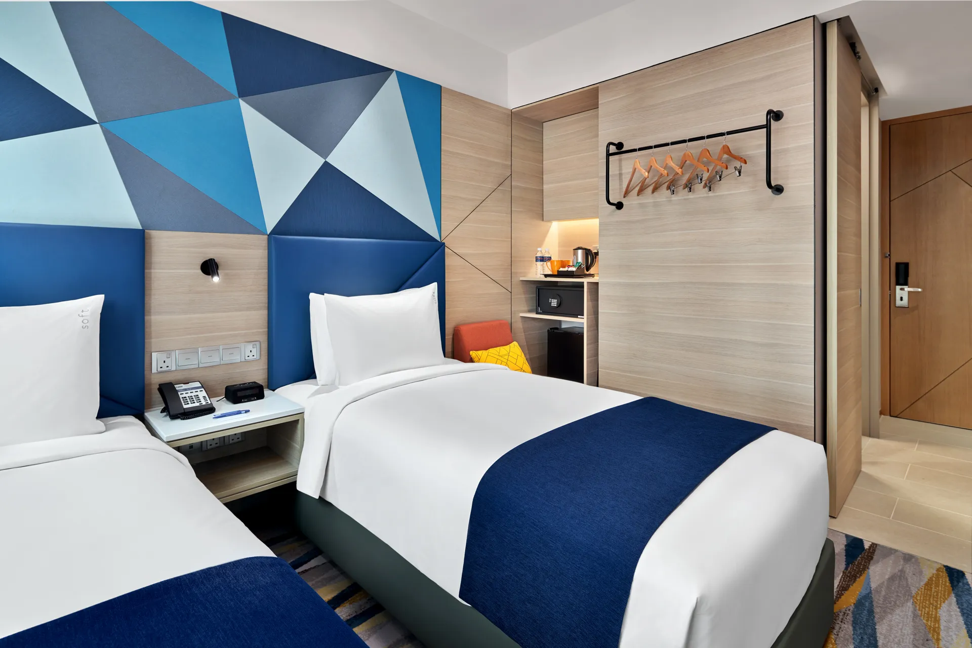 Twin room detail with wardrobe niche, minibar and patterned carpet — Holiday Inn Express Serangoon interior photography