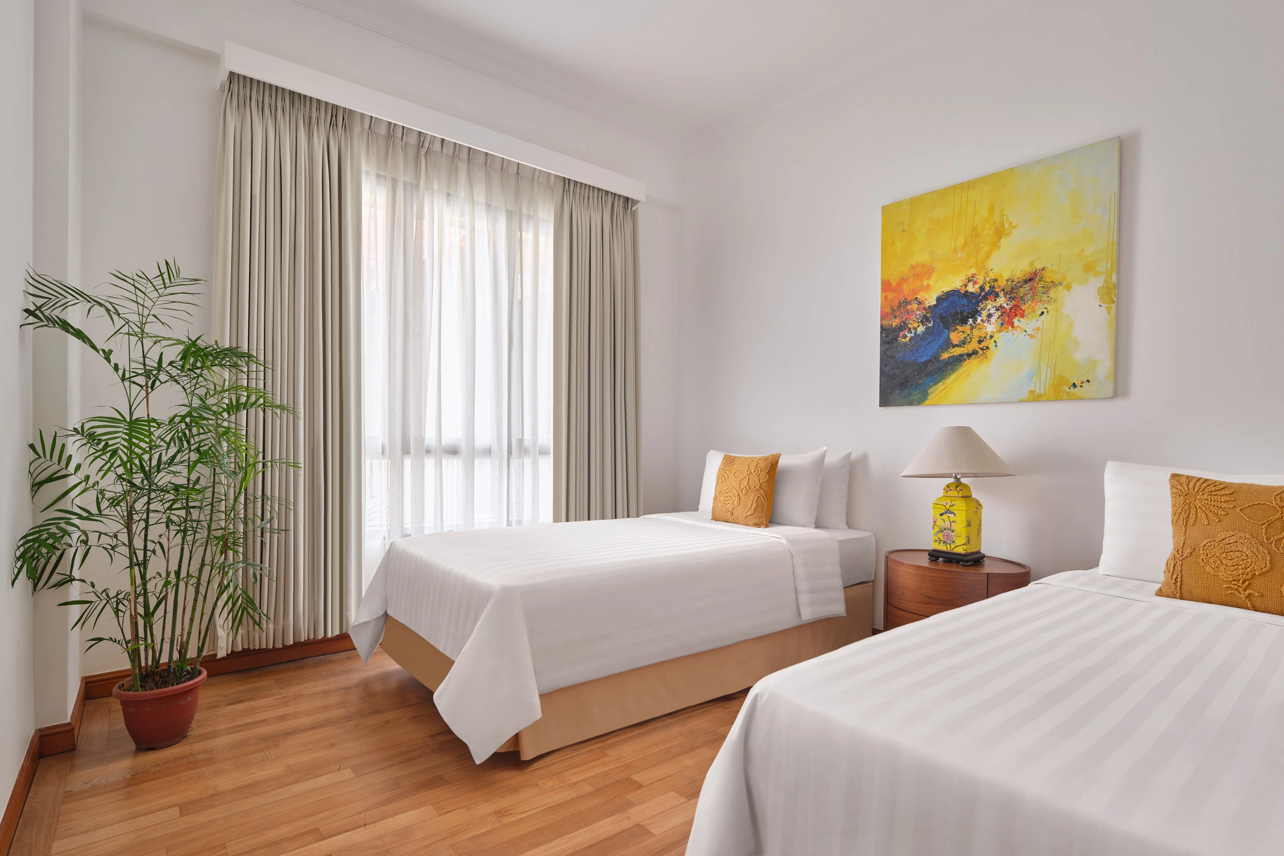 Twin bedroom with white linens, yellow accent art and palm plant, Shangri-La Residences Singapore