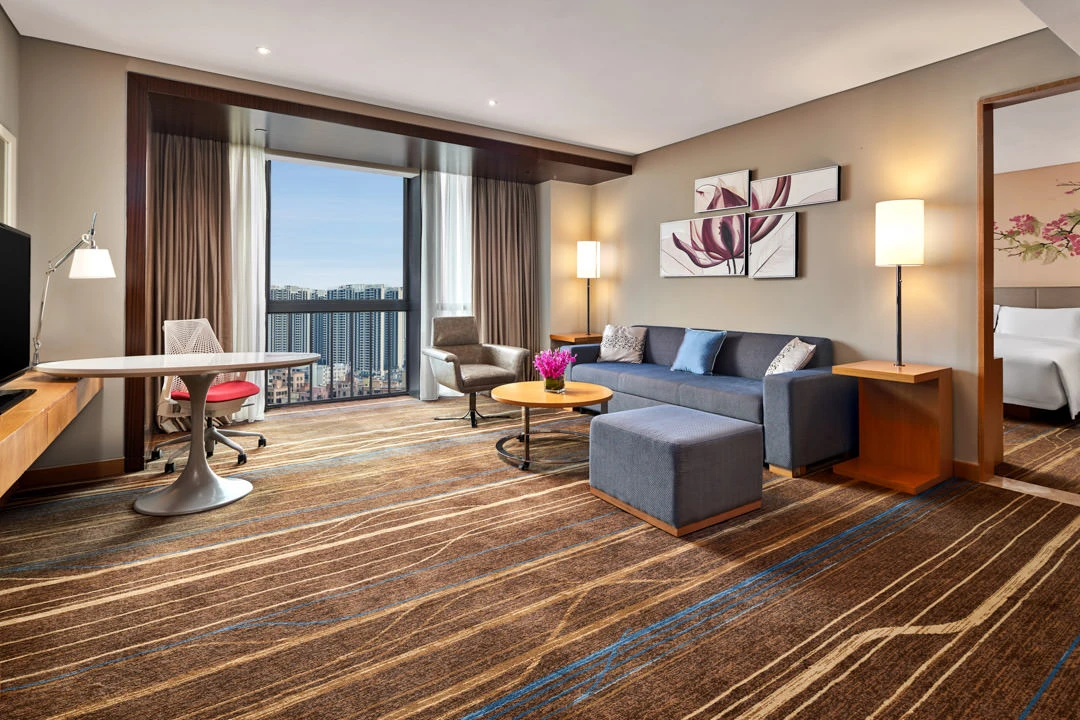 Suite living area with blue sofa, work desk and floral triptych