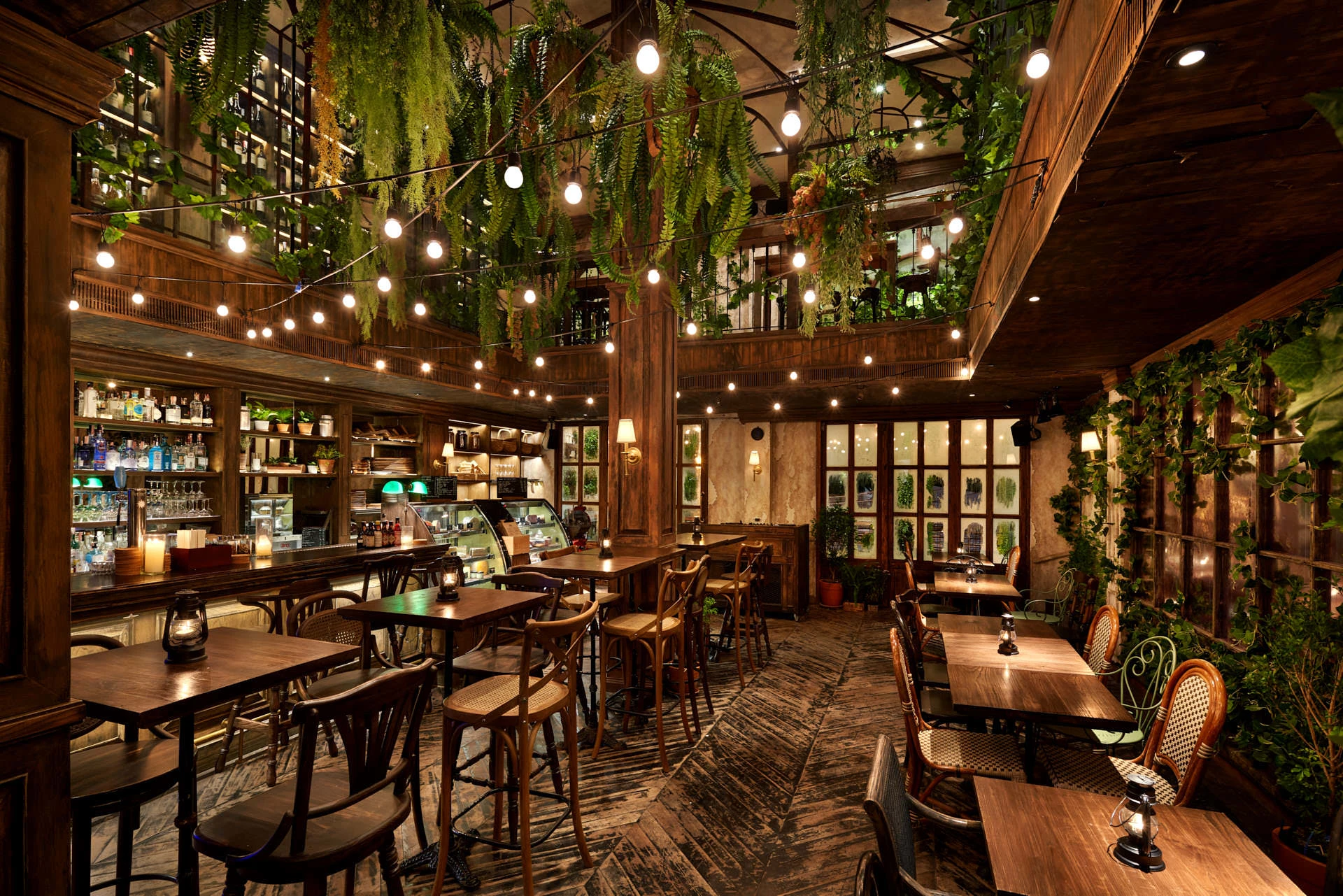 Dining room with bistro chairs, festoon lights and vine-covered mezzanine