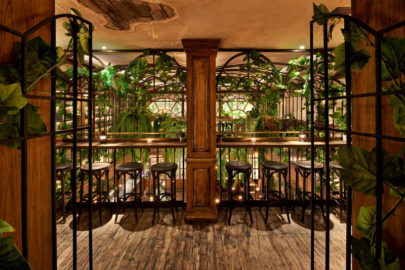 Wrought-iron gates framing mezzanine balcony with climbing vines