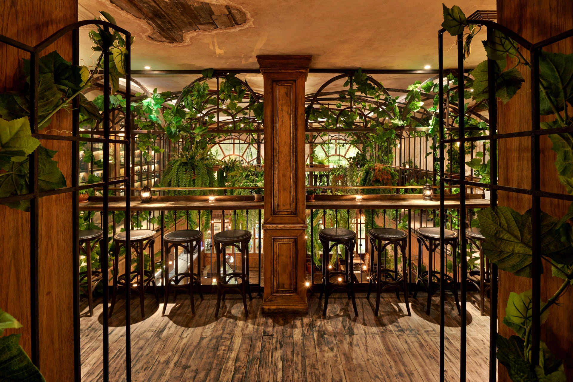 Wrought-iron gates framing mezzanine balcony with climbing vines