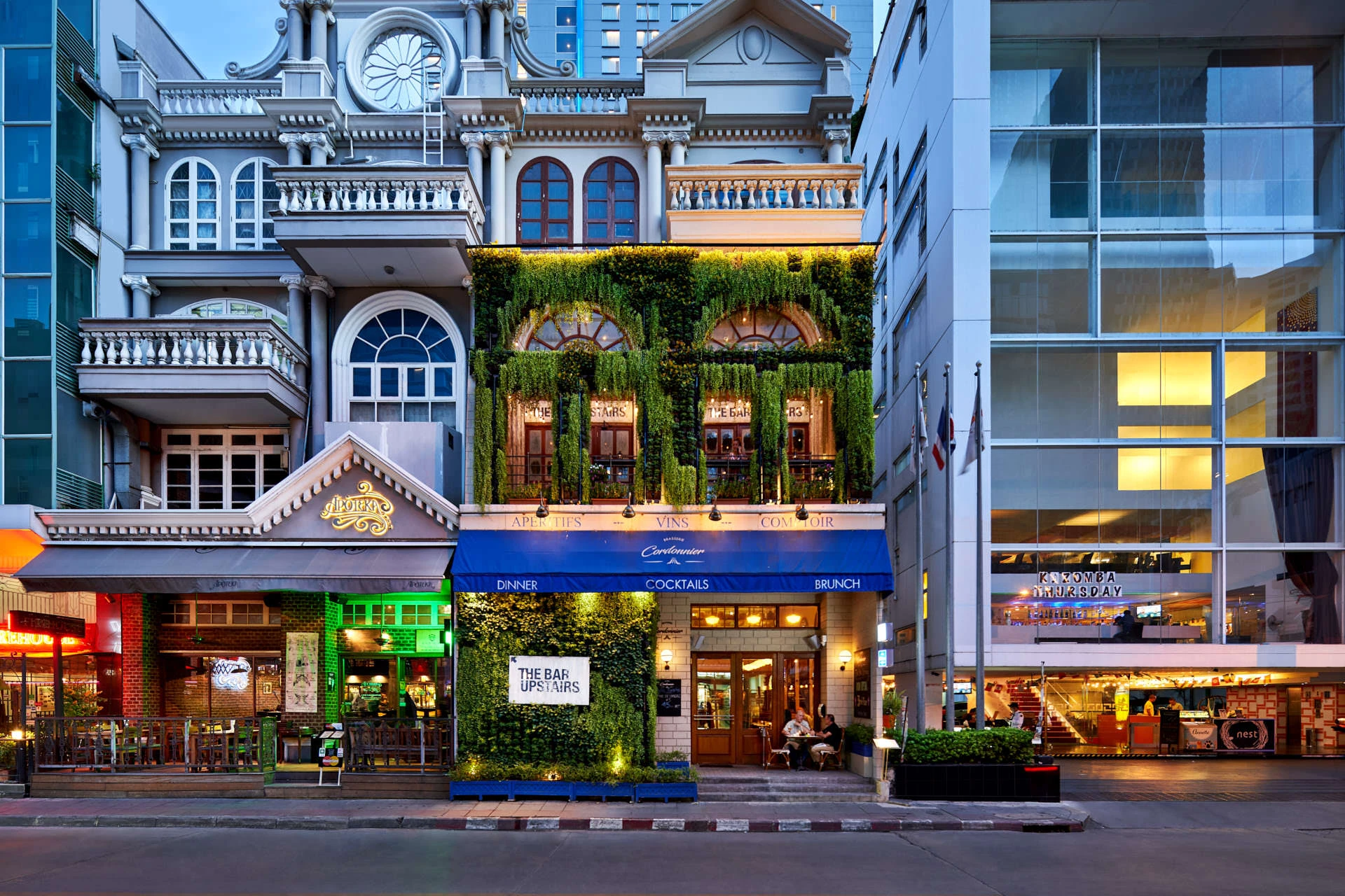 French facade with green wall and blue awning at twilight