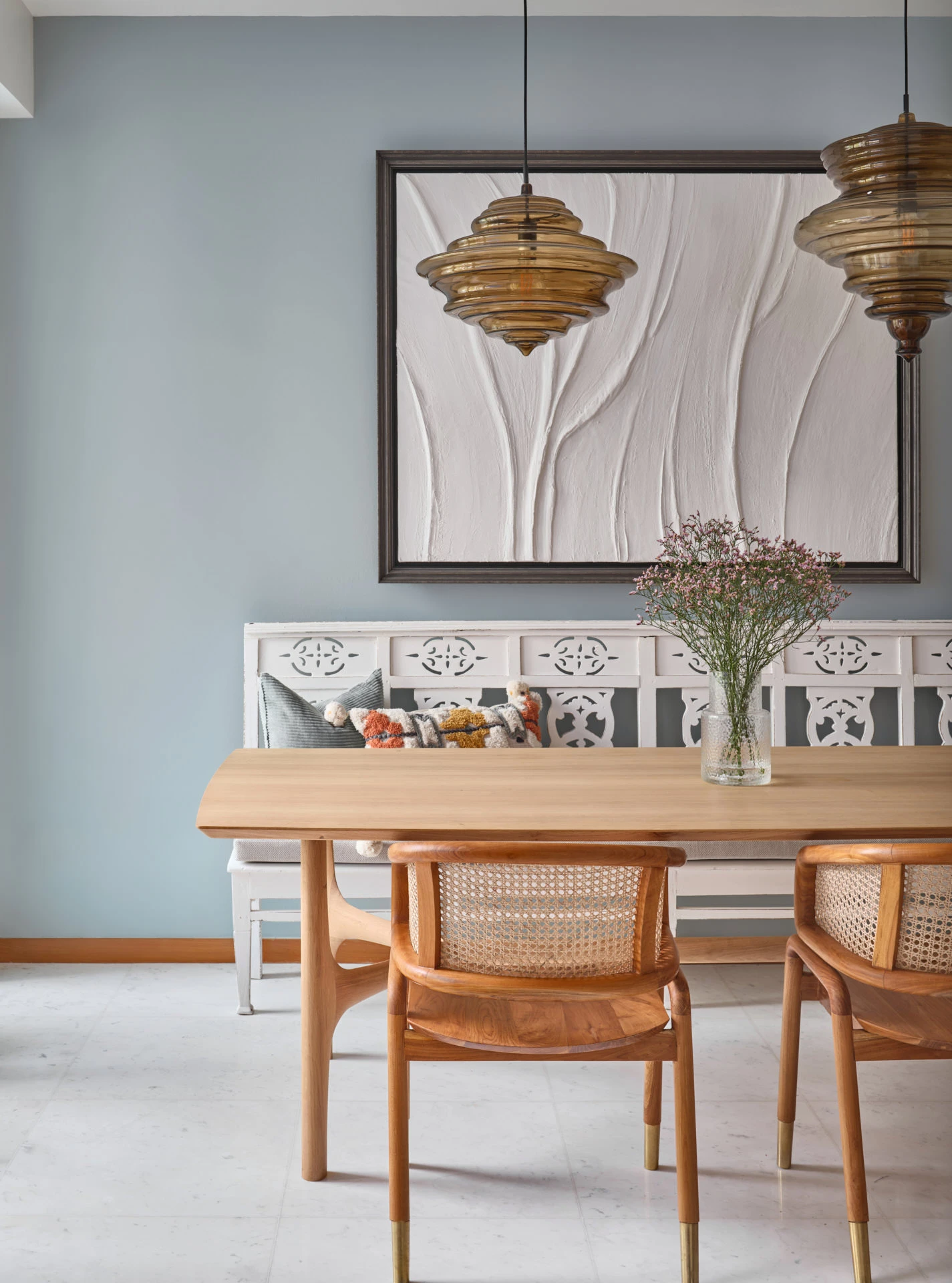 Dining nook with duck-egg walls, cane chairs and amber glass pendants
