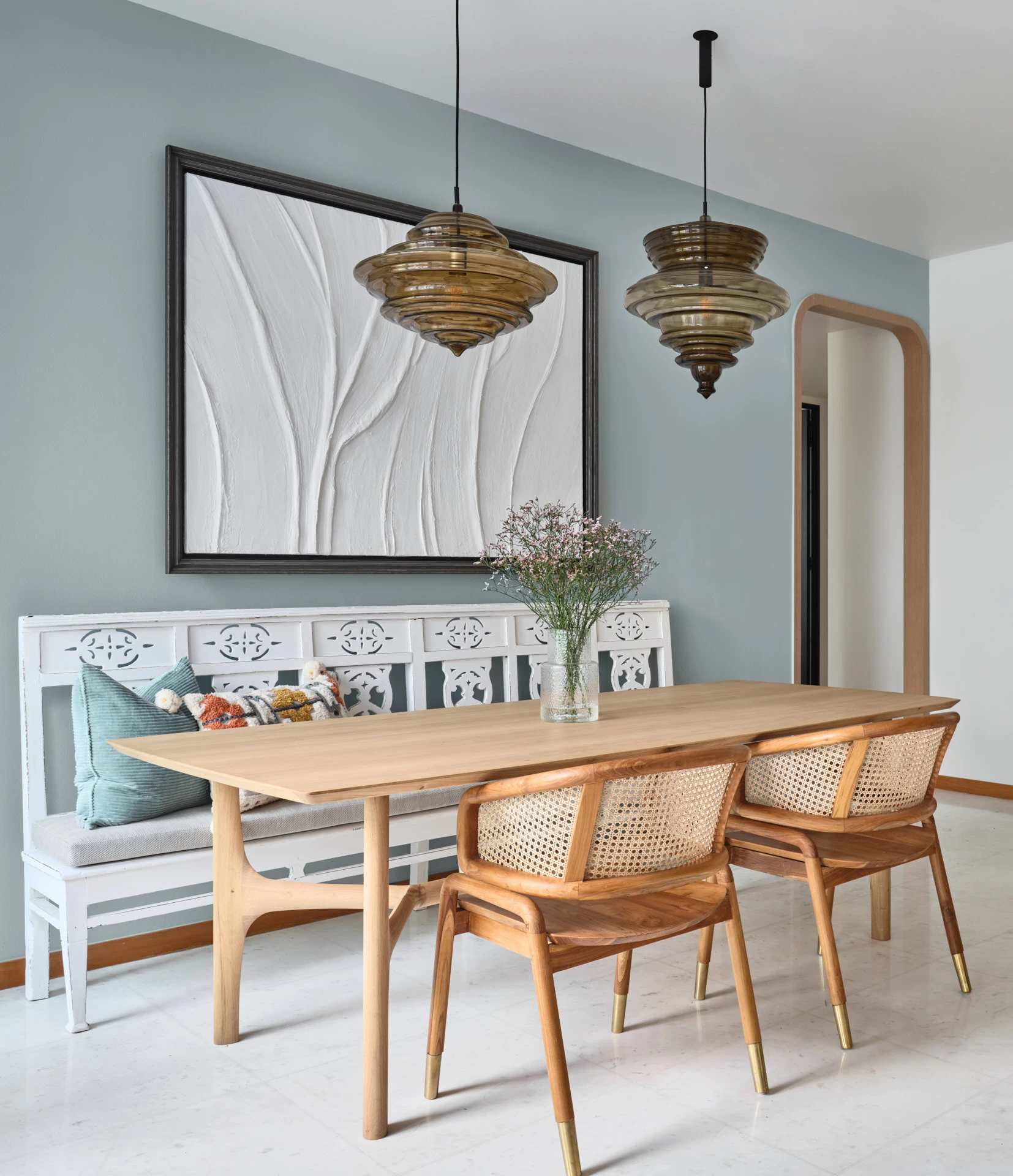 Dining area with carved bench, amber pendants and timber archway