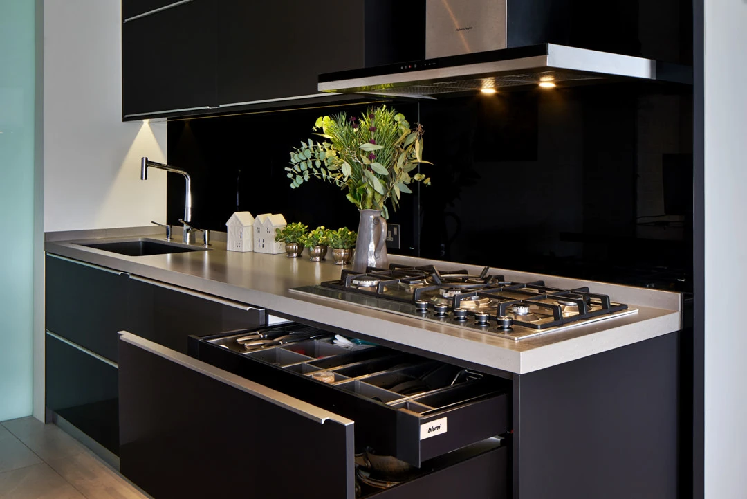Black kitchen with open drawers, protea arrangement and moody lighting