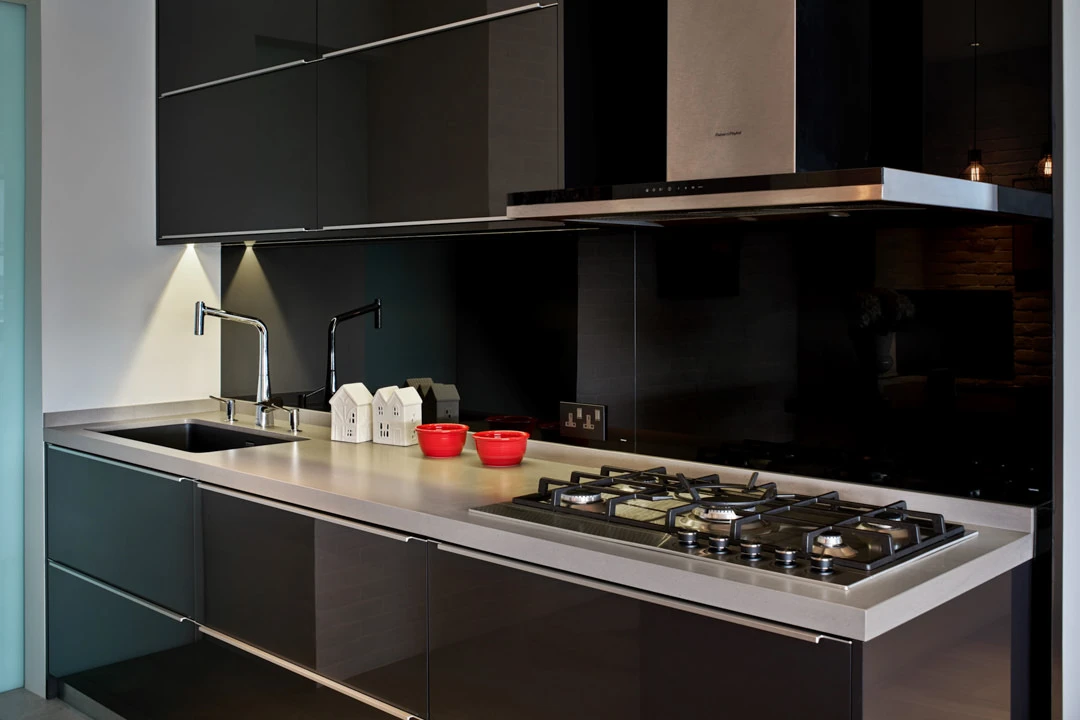 Black kitchen detail with chrome faucet and ceramic house ornaments