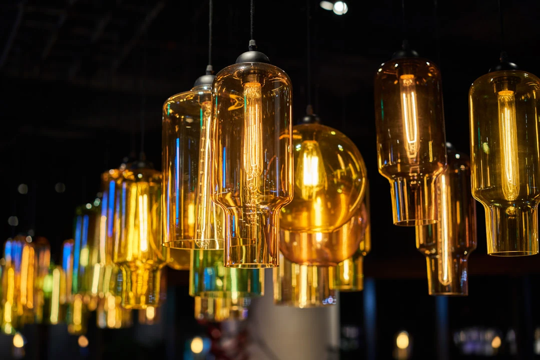 Amber and green blown-glass pendant lights with Edison bulbs — Crowne Plaza Beijing Lido interior detail photography