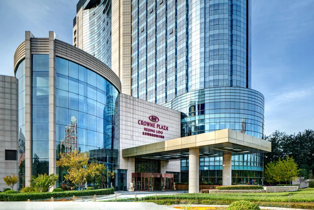 Curved glass facade with porte-cochere entrance and landscaped grounds — Crowne Plaza Beijing Lido architectural photography