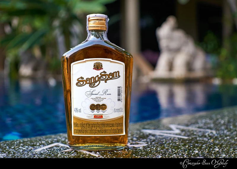 SangSom Special Rum bottle on stone poolside ledge with tropical backdrop