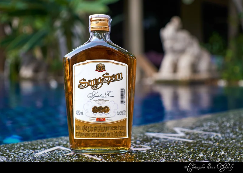 SangSom Special Rum bottle on stone poolside ledge with tropical backdrop