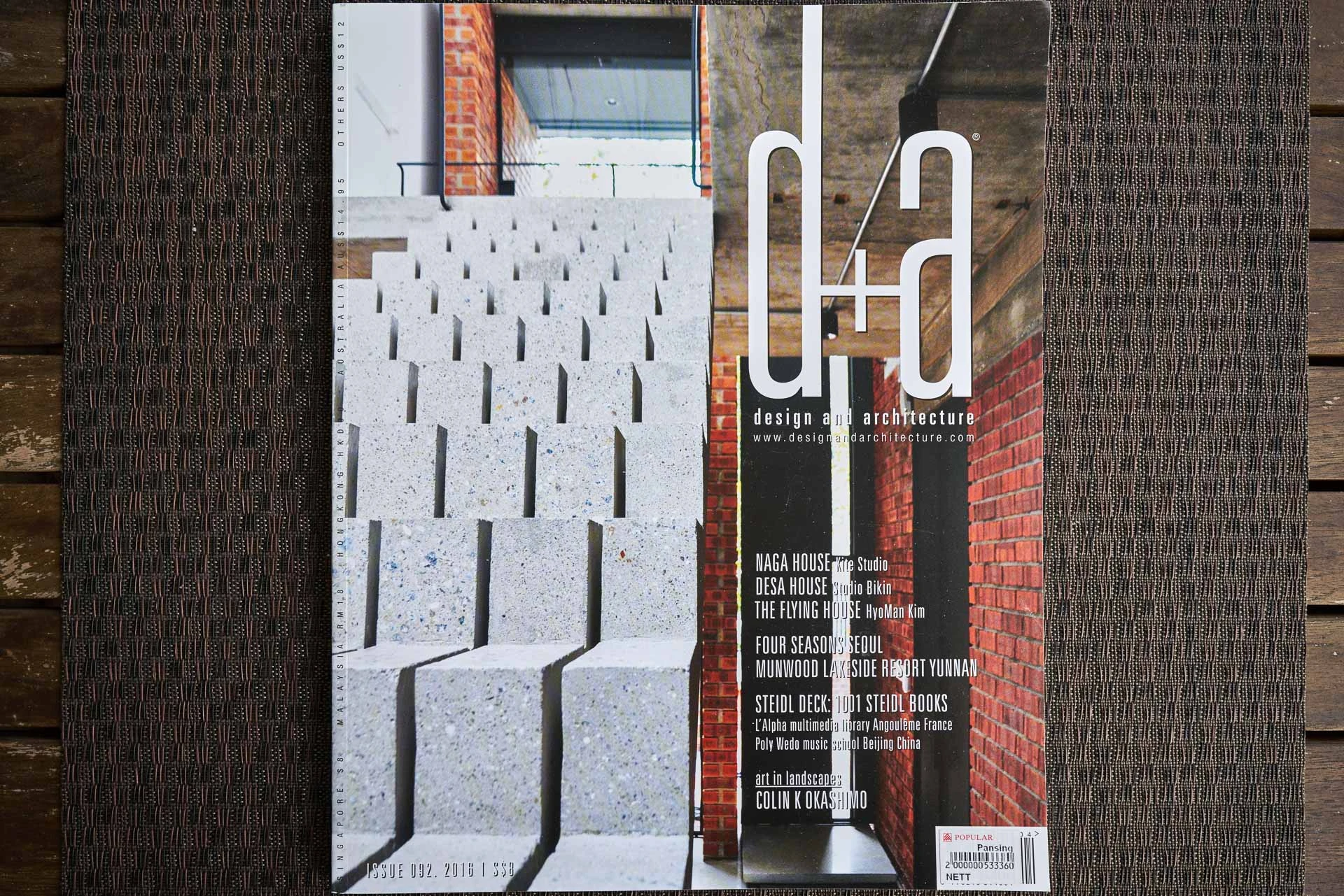 Design and Architecture magazine issue 92 cover on a dark wood surface, featuring concrete architectural details and a patterned facade.
