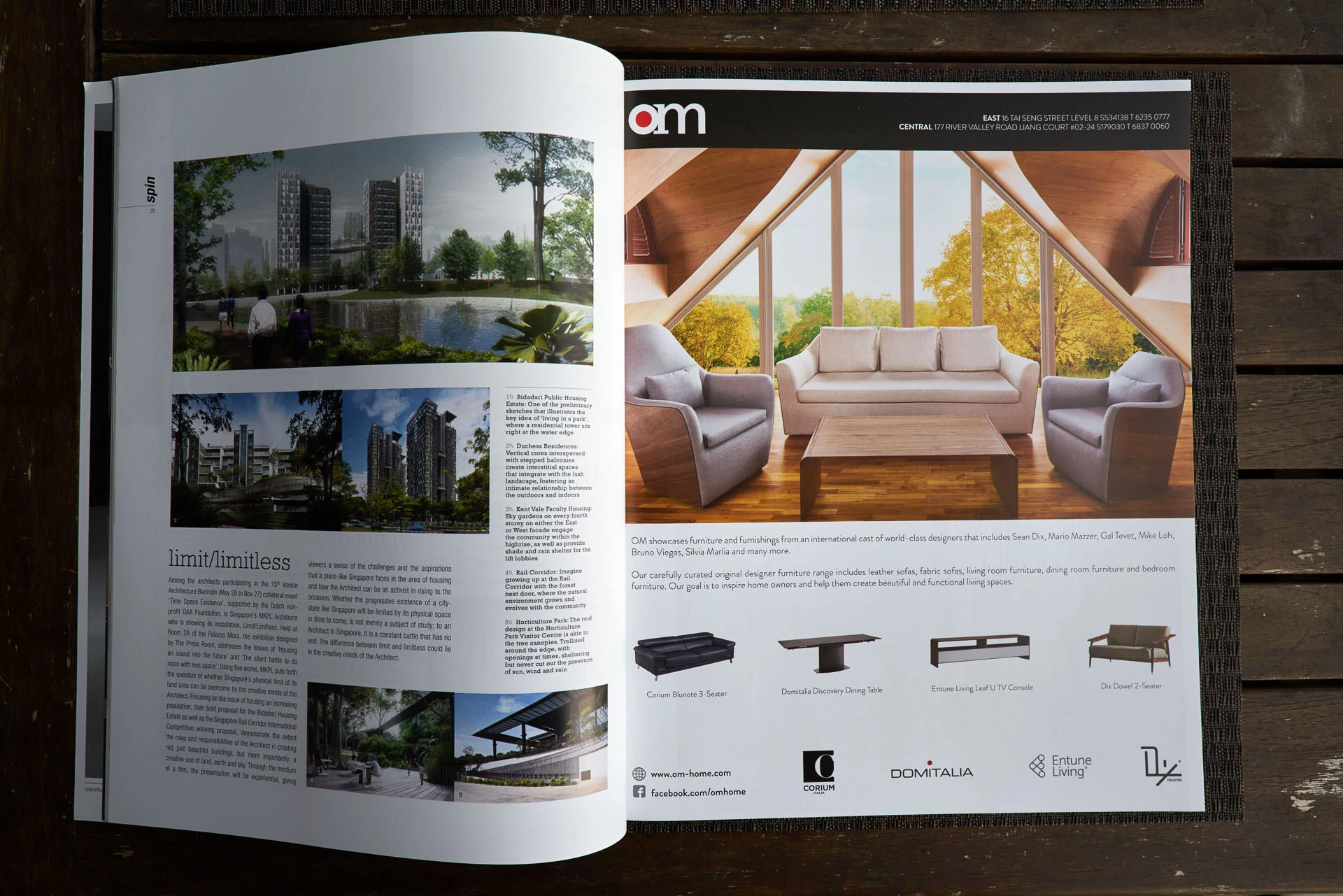 Open magazine spread on a wooden table showing an architecture article with building renderings on the left and a furniture advertisement on the right.