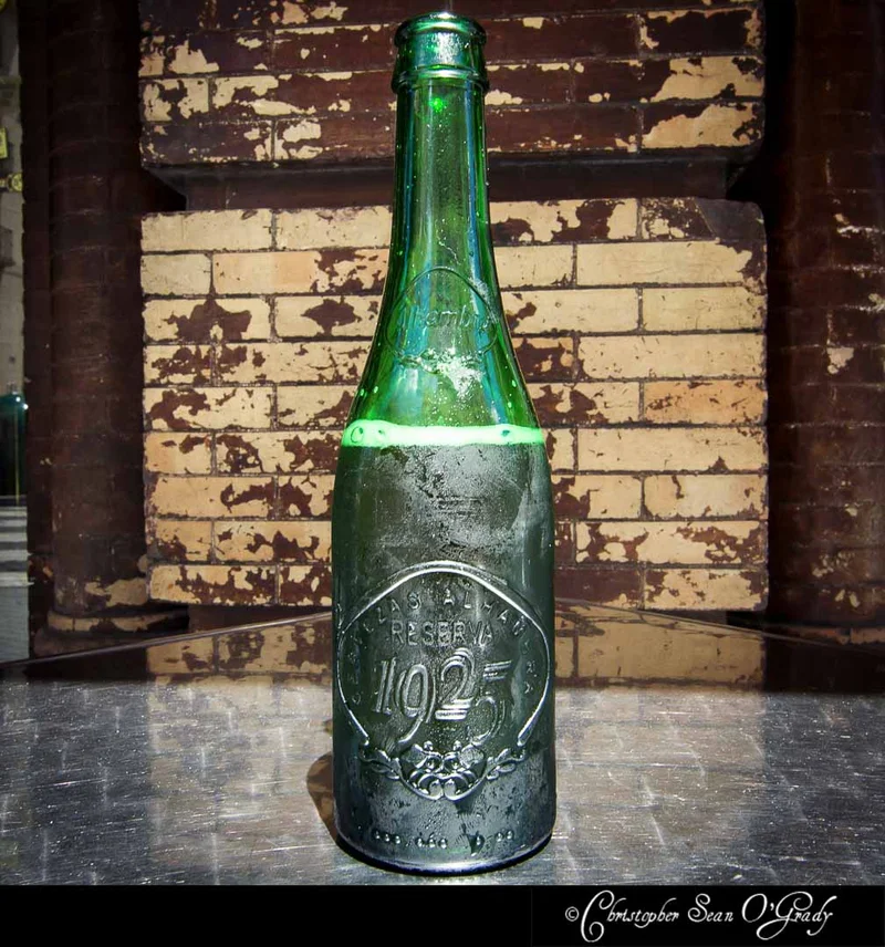 Alhambra Reserva 1925 green embossed bottle against weathered brick wall