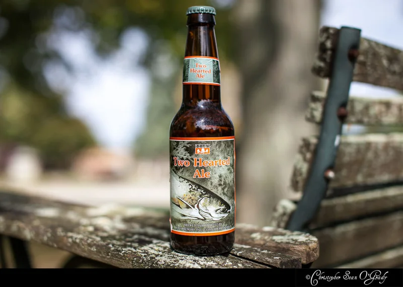 Bell's Two Hearted Ale on a weathered wooden bench outdoors