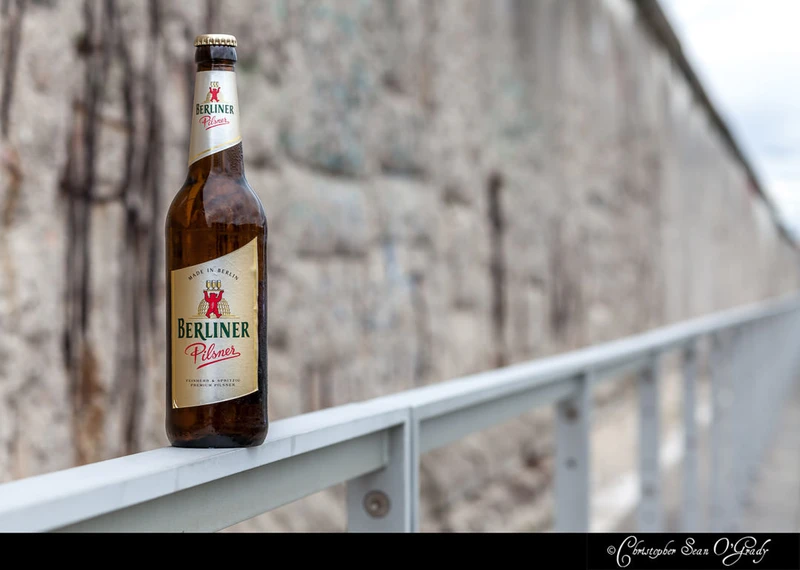 Berliner Pilsner on a metal railing at the Berlin Wall memorial