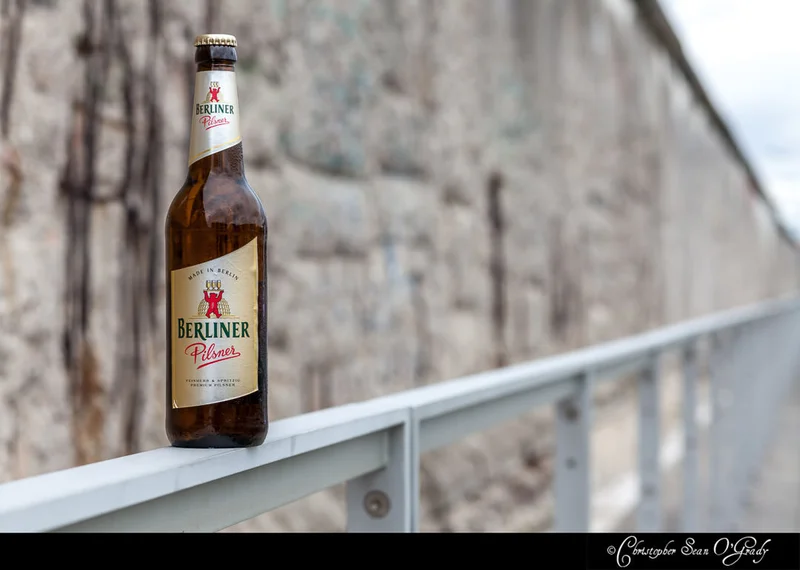 Berliner Pilsner on a metal railing at the Berlin Wall memorial