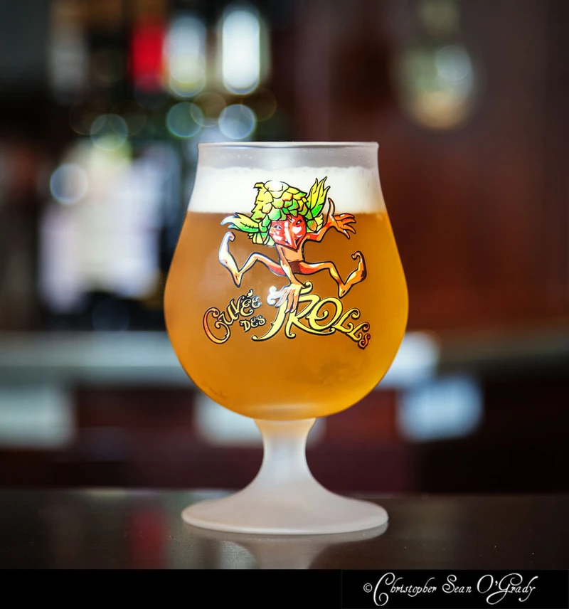 Cuvee des Trolls Belgian ale in branded tulip glass on a dark bar counter
