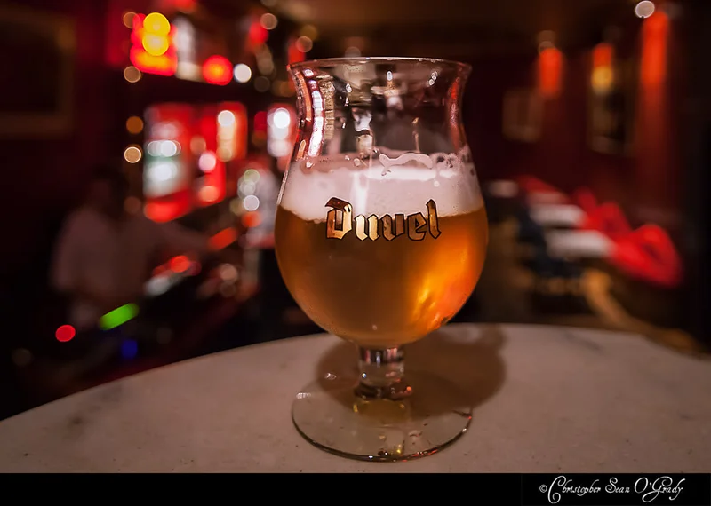 Duvel Belgian ale in branded tulip glass at a dimly lit red-hued bar