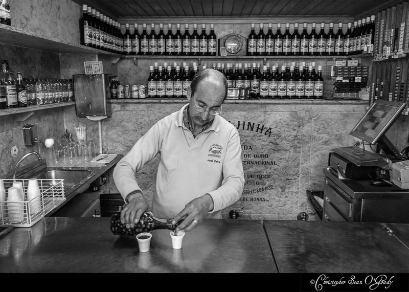 Ginjinha liqueur being poured by bartender at a traditional Lisbon bar
