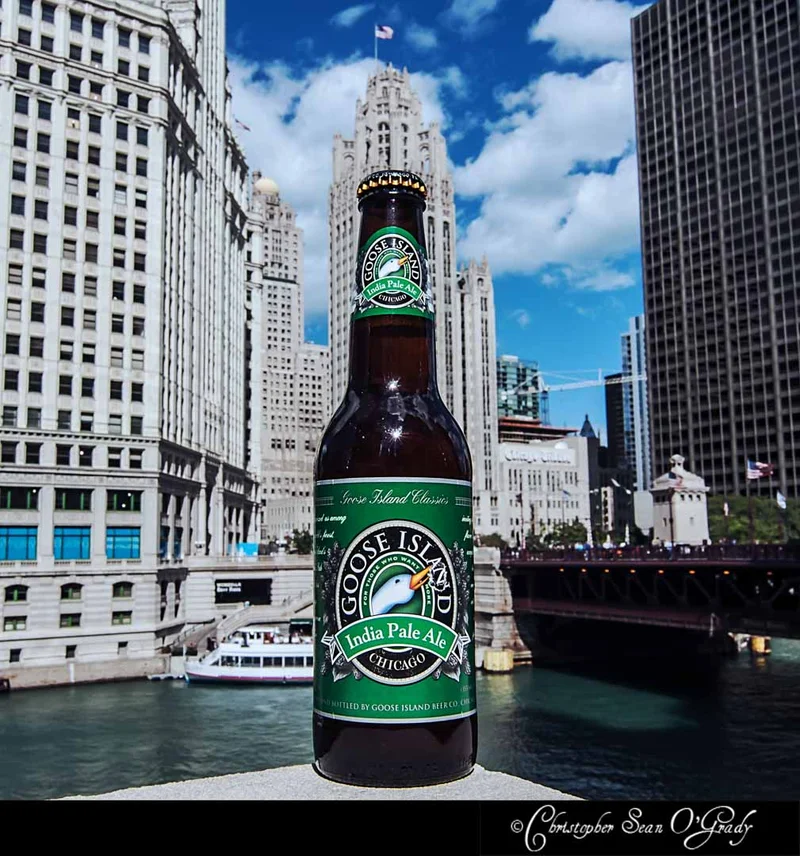 Goose Island India Pale Ale bottle on a ledge with Chicago River and skyline