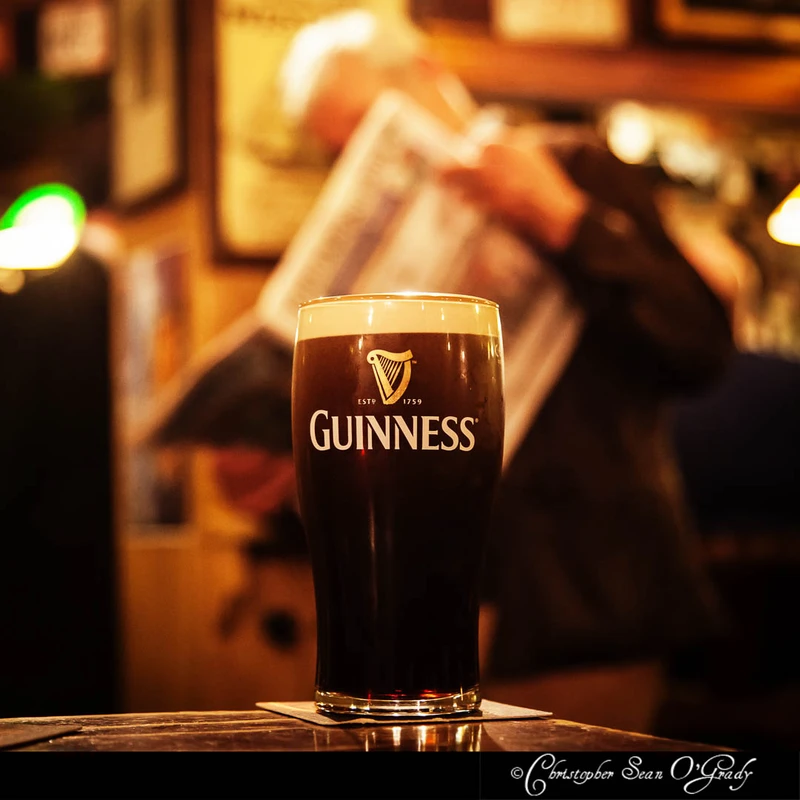 Guinness pint on a wooden bar in a warm dimly lit Irish pub