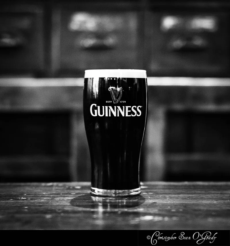 Guinness pint on a worn wooden bar in black and white