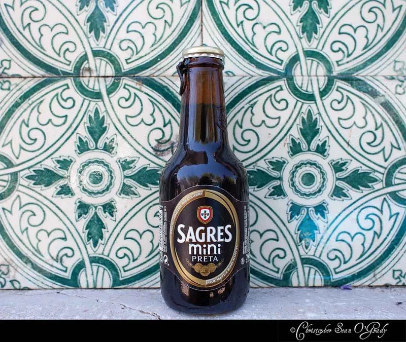 Sagres Mini Preta dark beer bottle on Portuguese green and white azulejo tiles