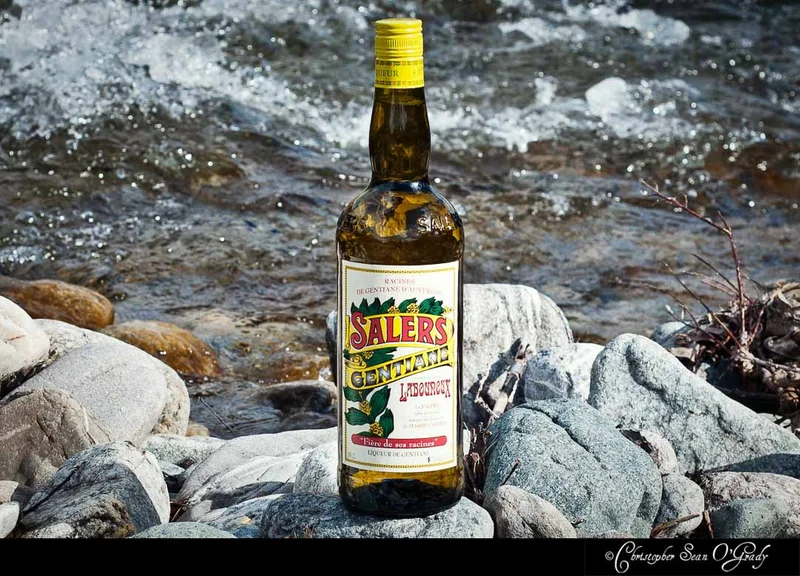 Salers Gentiane liqueur bottle on riverside rocks with flowing water