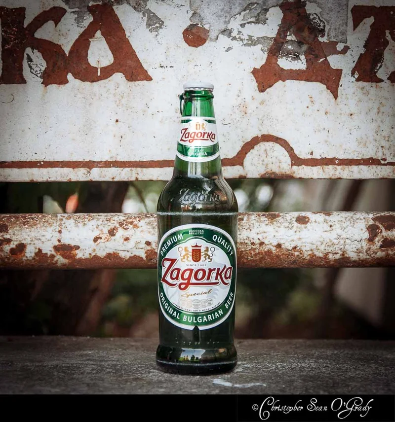 Zagorka Special Bulgarian beer bottle on a ledge with a rusty vintage sign