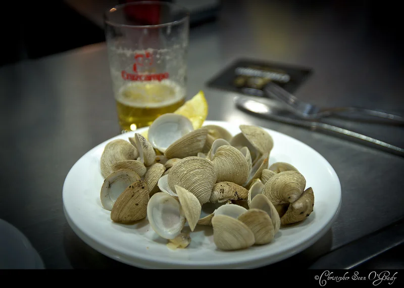 Cruzcampo beer with a plate of steamed clams at a Spanish tapas bar